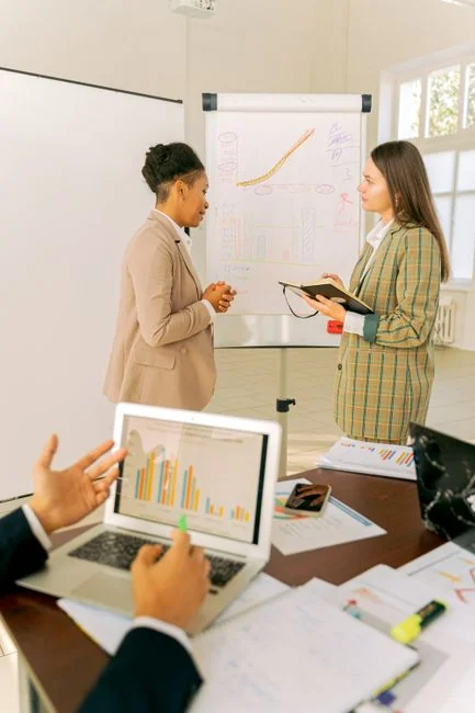 Person analyzes stock data with a smartphone and laptop, indoors.